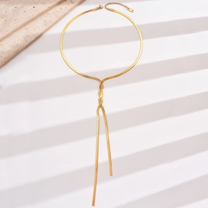Detail view of a long gold snake chain necklace made of polished stainless steel
