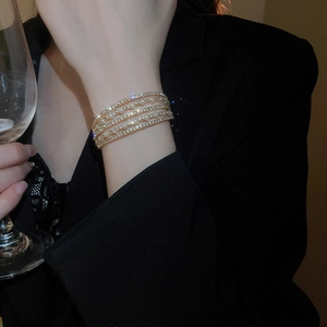 Close-up of luxury multi-layer gold bracelet with pearls and rhinestones on female wrist