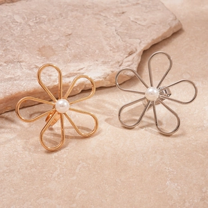 Hollow flower rings with white pearls in gold and silver finish on natural stone