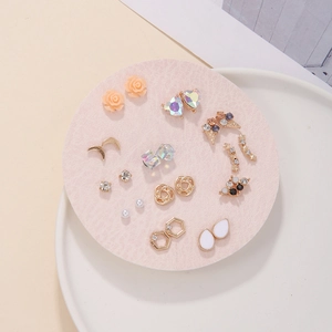 Close-up of 12 pairs of gold finish earrings featuring pearls and assorted geometric shapes