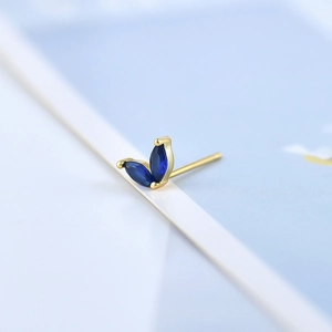 Macro detail of gold earring with two marquise-cut deep blue zircon stones in petal design