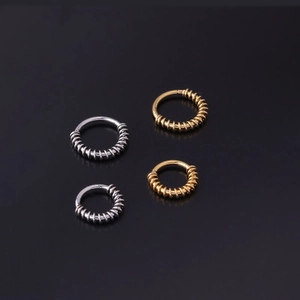 Vue détaillée de piercings de nez en spirale dorés et argentés sur fond sombre