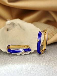 Macro detail of rectangle gold earrings with blue enamel and sparkling zircon on shell