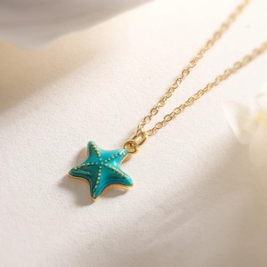 Vue macro d'un collier pendentif étoile de mer bleue avec des points dorés sur fond blanc