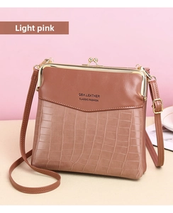 Close-up of light pink crossbody bag featuring faux crocodile leather and metal hardware