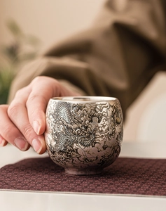 Gros plan du motif de dragon gravé sur une tasse à thé en céramique argentée de kung-fu