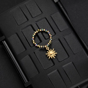 Detailed close-up of a beaded ring with colorful gemstones and a golden sun pendant