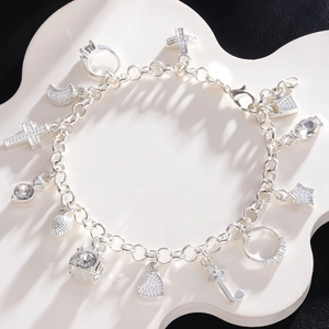 Fashion silver charm bracelet with cross, heart, moon and star pendants on white stand