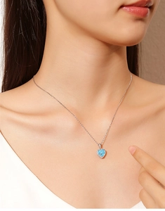 Detail of S925 silver necklace featuring a heart-shaped blue gemstone pendant on a model