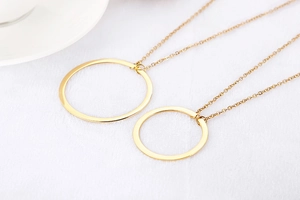 Detailed view of two hollow geometric circle pendant necklaces in golden finish
