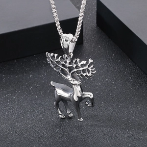 Macro shot of a polished silver stag pendant with artistic antlers on black texture