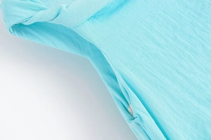Détail macro de la robe en maille bleu clair montrant les coutures et la texture du tissu