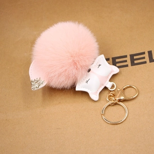 Detailed close-up of pink fluffy fox fur pompom keychain with golden metal clasp hardware