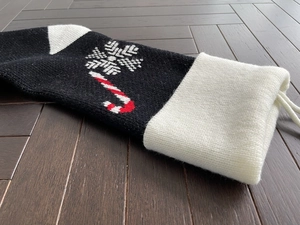Close-up of black knitted Christmas stocking with white snowflake and candy cane patterns