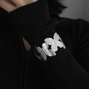 Detail of silver butterfly open bangle with layered butterfly charms on female wrist