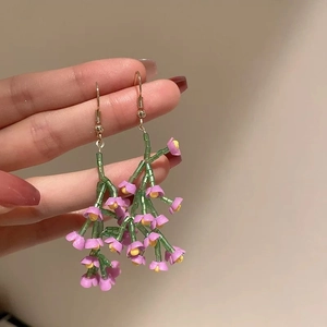 Detailed shot of handmade beaded flower earrings featuring pink and green seed beads