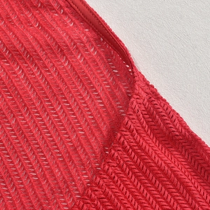 Macro detail of red hollow knit fabric showing V-shaped weave and edge stitching textures