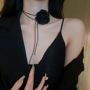 Detail of a handmade black fabric rose necklace worn by a model in a vintage style