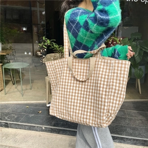 Detail of checkered canvas tote bag with dual straps worn over the shoulder for commute