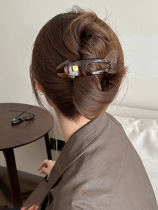 Macro detail of high quality amber resin hair claw clip with golden accent on hair