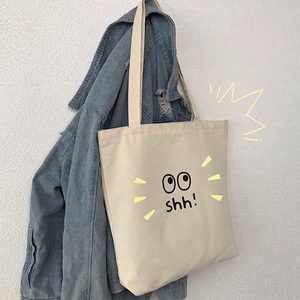 Bolso tote de lona beige con estampado de ojos de dibujos sobre chaqueta vaquera