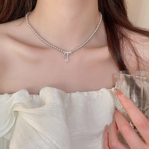Détail du collier à perles argentées avec un pendentif raffiné serti de brillants