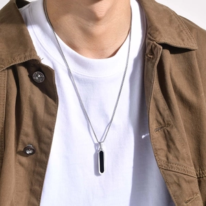 Detail shot of a geometric silver pendant necklace with black inlay on a male model
