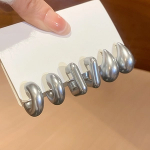 Detailed view of matte silver earring set featuring hoop, U-shape and teardrop designs