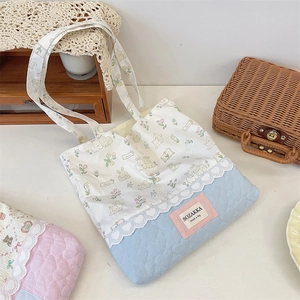 Close-up of quilted floral tote bag with lace trim and cartoon rabbit patterns
