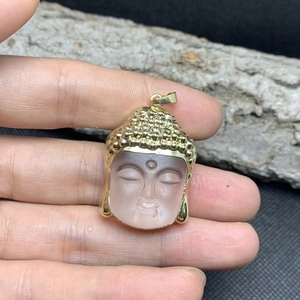 Macro detail of a crystal glass Buddha head pendant with golden metal accents and matte finish