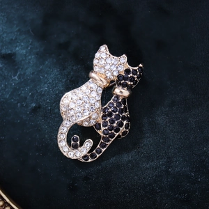 Detail of artistic twin cat brooch with black and white rhinestones on velvet background