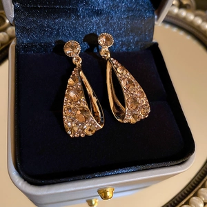 Detailansicht goldener hohler Tropfenohrringe mit Kristallen in einer Samtschmuckschatulle