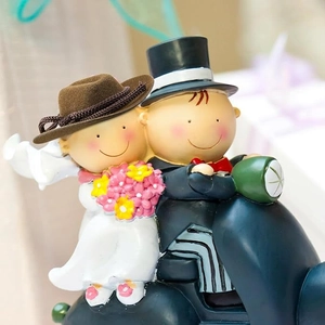 Close-up of resin wedding cake topper with bride and groom on a blue motorcycle