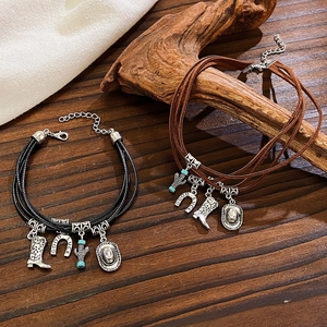 Detail of western bohemian multilayer leather bracelets with cowboy hat and boot charms
