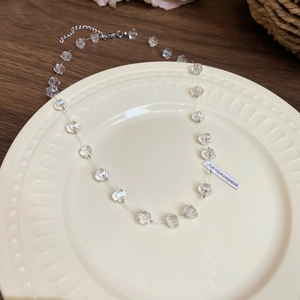Detail of colorful crystal bead necklace on ceramic plate with metal clasp and gift tag