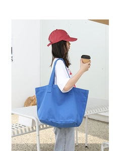 Detailed texture of blue washed canvas tote bag worn over the shoulder in outdoor setting