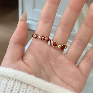 Close-up of vintage gold rings with red enamel floral and heart patterns for women