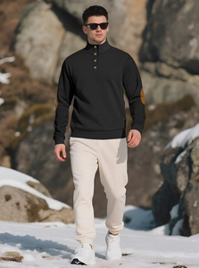 Detail of men's black knit sweater with gold buttons and brown leather elbow patches