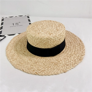 Detail of hand-woven raffia sun hat featuring a classic black ribbon and textured wide brim