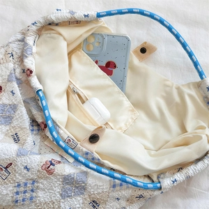 Detail view of the quilted tote bag interior with a zipper pocket and bear print