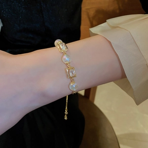 Detail of adjustable golden bracelet with mermaid pearls and rectangular zirconias