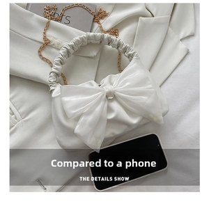 Close-up of cream bow bag showing cloud-shaped pleats and comparison with a phone