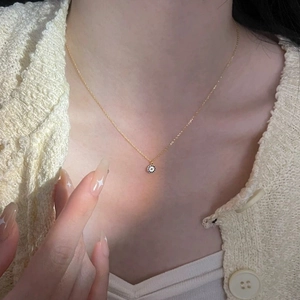 Close-up of a 14K gold-plated silver evil eye pendant necklace worn by a model