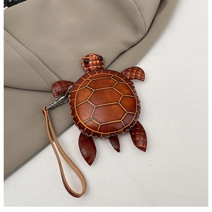 Détail d'un mini sac tortue en cuir marron avec coutures fines et fermoir en métal argenté