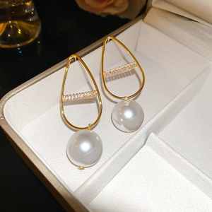 Macro detail of gold-plated hollow teardrop earrings with crystals and white pearls