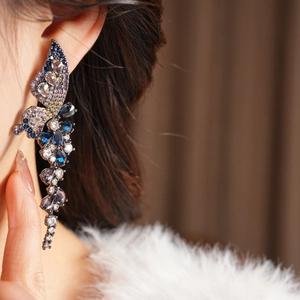 Détail de la boucle d'oreille papillon vintage avec cristaux multicolores sur l'oreille