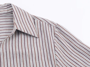 Detail of striped shirt collar and shoulder with grey, deep red and beige vertical lines