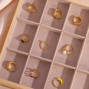 Flat lay of nine gold-plated rings in various styles displayed in a wooden jewelry box