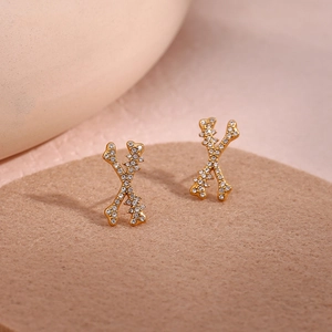 Chic gold X-shape bone earrings with crystal pavé setting on minimalist display