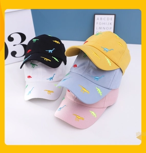Detailed view of colorful embroidered dinosaur patterns on multiple kids baseball caps